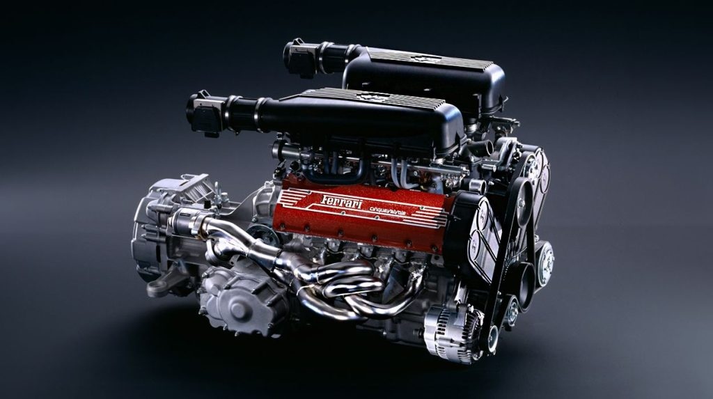 Specialist mechanic servicing a Ferrari F355 engine bay — torque wrench on the red crackle cam covers